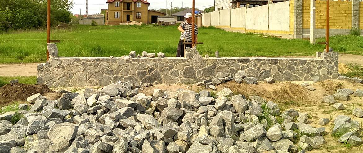 Надёжный и добротный забор из камня: обзор материалов и варианты исполнения